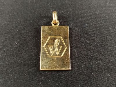 un pendentif en or sur lequel est gravée la lettre « w »