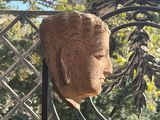 a statue of a head on a table in front of a fence