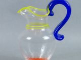 a glass pitcher with a blue handle and a yellow handle
