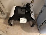 a small black and white machine sitting on a tiled floor