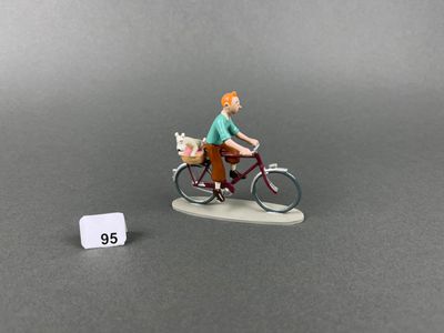 a figurine of a man riding a bike with a dog in a basket