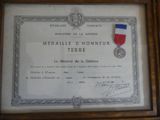 framed photograph of a medal and certificate on display in a wooden frame