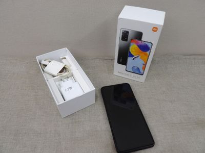 une image représentant une boîte contenant un téléphone, posée sur un canapé