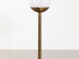 une lampe de table en laiton surmontée d'un abat-jour sphérique en verre