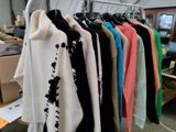 a lot of sweaters hanging on a rack in a room