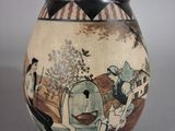 a vase with a painting on it sitting on a table