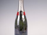 une bouteille de champagne posée sur une table blanche, sur fond gris