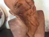 un buste d'homme barbu posé sur une table, à côté d'un vase