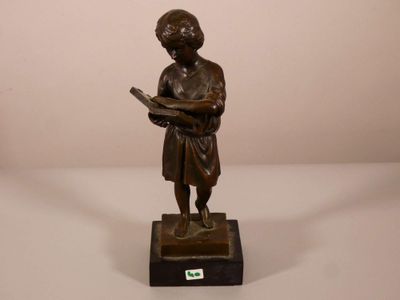 statue en bronze représentant un garçon en train de lire un livre, posée sur un socle en marbre