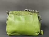 the green purse is sitting on the table with a chain around it