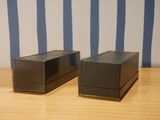 two black boxes sitting on a table with a striped wall behind them