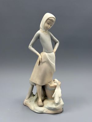 figurine représentant une femme debout sur un rocher, un panier à la main