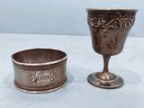 une paire de gobelets en argent et une coupe en argent posés sur une table