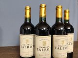 three bottles of red wine sit on a table in front of a blue wall