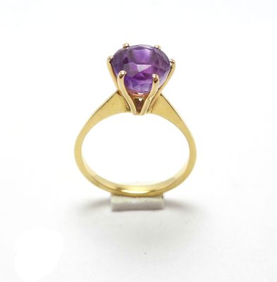 gros plan d'un anneau de pierre violette sur une surface blanche