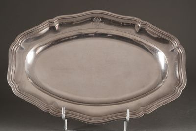 un plat en argent ancien posé sur un socle, sur fond noir