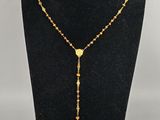 un collier chapelet en or orné d'une croix, posé sur un mannequin noir