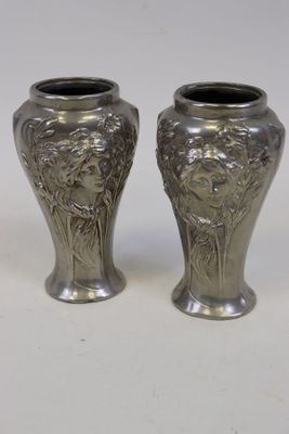 une paire de vases en argent ornés de visages sur un fond blanc