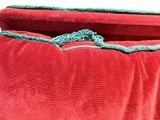 a red bag with a green handle sitting on a white surface
