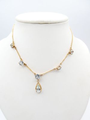 a gold necklace with blue and white crystals on a mannequin