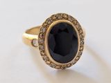 un gros plan sur une bague en or sertie d'une pierre noire entourée de diamants blancs