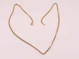 un collier en or avec un pendentif en forme de cœur sur une chaîne