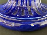 a blue glass vase with a yellow flower on top of it