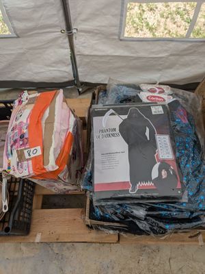 un chat assis sur une palette à côté d'une pile de vêtements