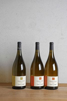 trois bouteilles de vin sont alignées sur une table en bois