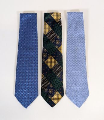 three ties are lined up on a white surface, one is blue and the other is yellow