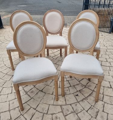 six chairs with white upholstered seats are arranged in a circle