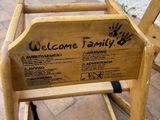 a wooden chair that has a welcome family sign on it