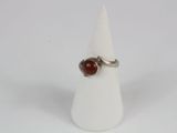 silver ring with a red stone on a white cone