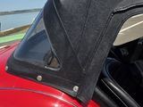 une voiture rouge au toit noir garée sur le bord de la route