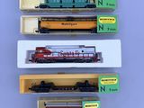 four different model trains are in boxes on a table