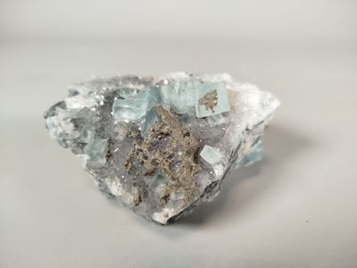 crystal cluster with blue and white crystals sitting on a white surface