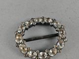 a close up of a silver broochle on a white surface