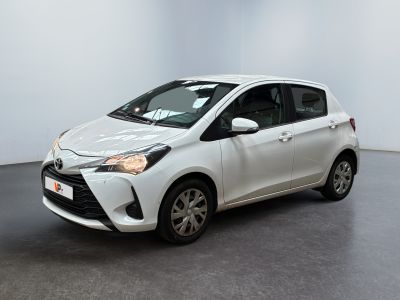 La Toyota Yaris est garée dans une pièce blanche au sol noir.