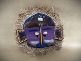 a close up of a mask with feathers on a wall
