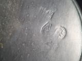 a close up of a person holding a metal pan with a stamp on it