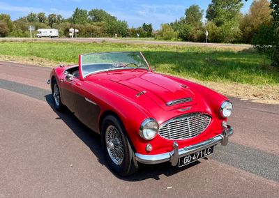 une voiture rouge qui roule sur une route de campagne