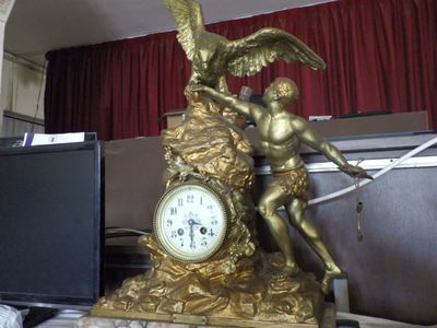 a statue of a man holding a clock on a desk