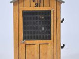 une petite cabane en bois avec une porte et deux oiseaux posés dessus