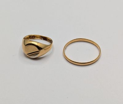 two gold rings sitting on top of each other on a white surface