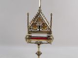 un coffret richement décoré, doré et rouge, surmonté d'une croix