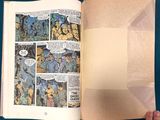 someone is holding a comic book open on a blue surface