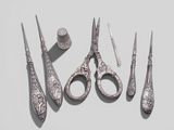 five pairs of scissors and a nail brush on a table