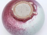 a red and white vase with a hole in it