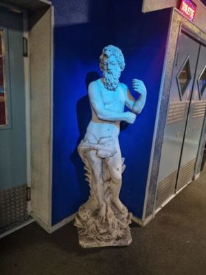 une statue représentant un homme debout devant un mur bleu