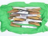 a lot of knives that are laying on a green cloth